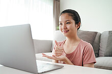 Junge Frau gebärdet vor einem Laptop